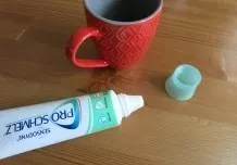 Getrocknete Kaffeeränder auf dem Tisch mit Zahnpasta entfernen