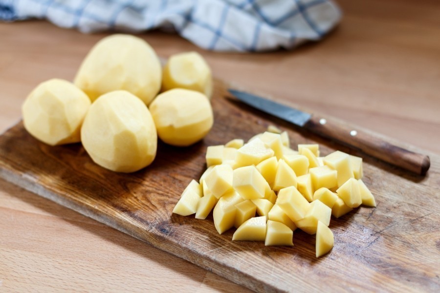 Die Kartoffeln schälen und in mundgerechte Stücke würfeln, dann kartoffelweich in Salzwasser kochen.