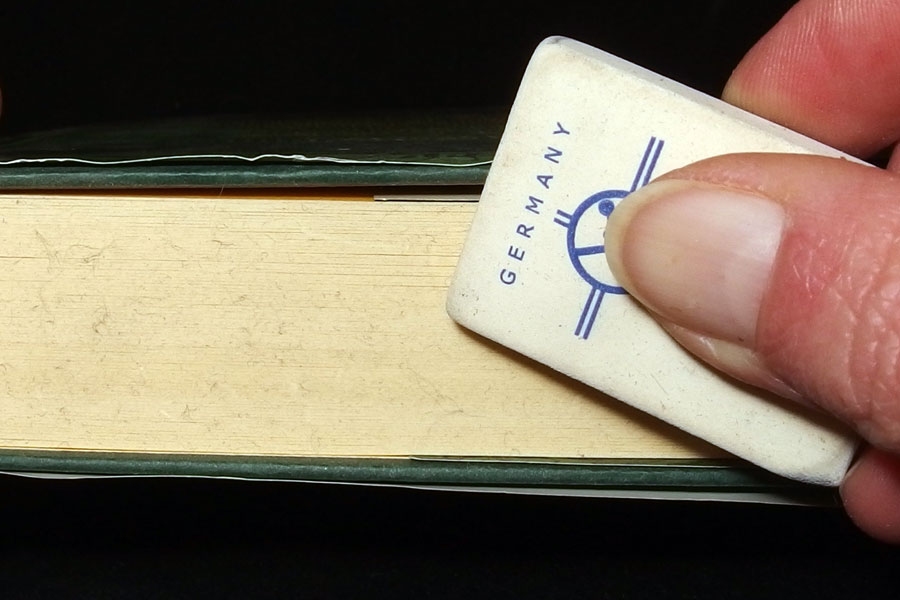 Fingerabdrücke und andere Schmutzspuren auf dem Schnitt eines Buches mit einem Radiergummi, und wenn das nicht hilft, mit feinem Schmirgelpapier entfernen.