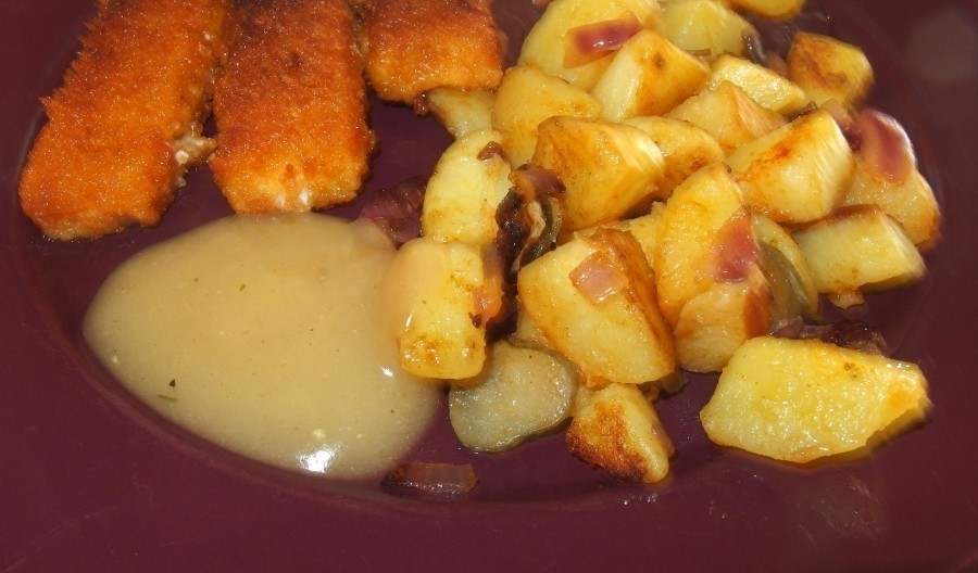 Fischstäbchenpfanne mit Kartoffeln und Gewürzgurken, serviert mit einer Senfsauce und garniert mit Petersilie.