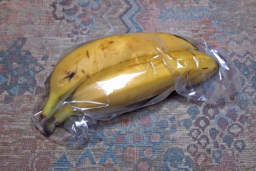 Bananen länger haltbar machen, indem man sie fest in eine Plastiktüte wickelt.