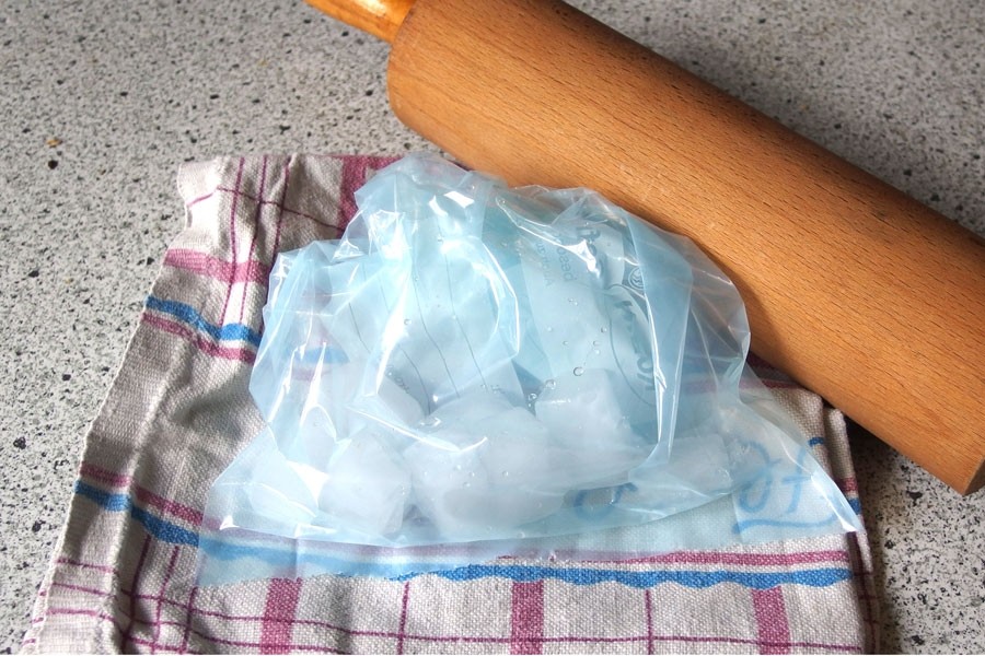 Eiswürfel zerkleinern: Eiswürfel in die Plastiktüte füllen, mit Geschirrhandtuch umwickeln und dann mit Hammer oder Nudelholz auf einer festen Unterlage zerschlagen.