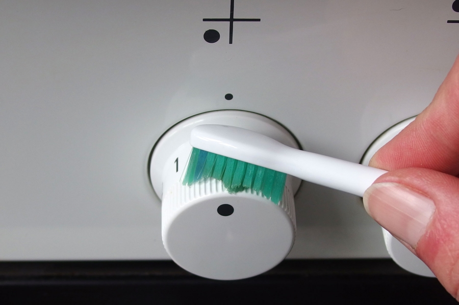 Die Schalter eines Elektroherds lassen sich mithilfe von Glasreiniger und einer Zahnbürste reinigen.
