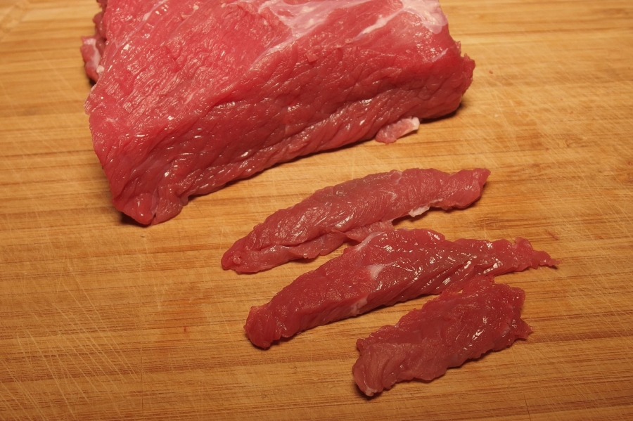 Fleisch kann man ganz einfach und blitzschnell in feine Streifen schneiden, wenn man es 1 1/2 bis 2 Stunden in den Gefrierschrank legt.