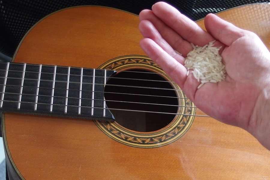 Den Hohlraum einer Gitarre von Staub befreien, mithilfe von Reis.