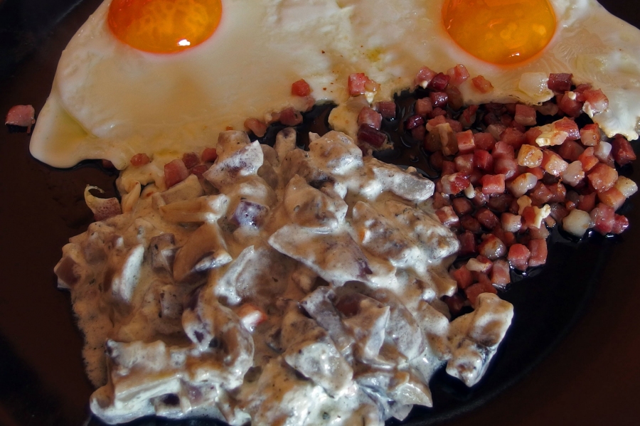 Leckere Rahm-Champignons mit Speck und Ei aus der Pfanne.