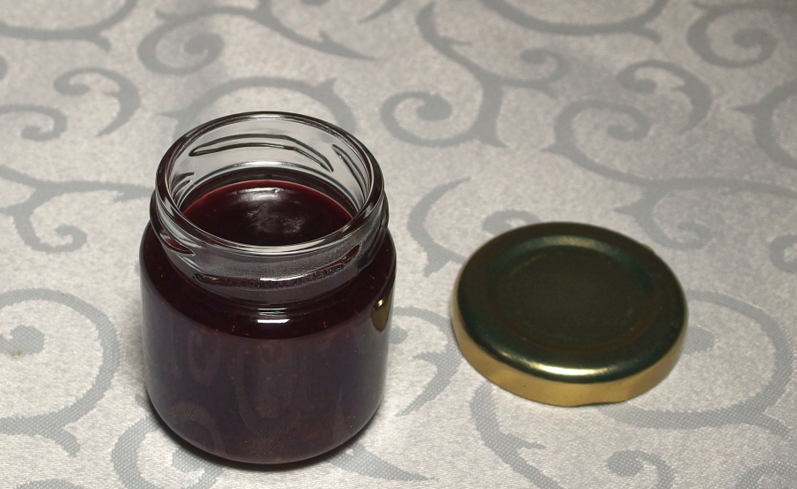 Selbst gemachte Marmelade mit einem Trichter sauber in Gläser einfüllen.