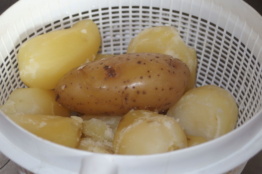 1-1,5 kg feste Kartoffeln kochen, noch heiß schälen und in Scheiben schneiden