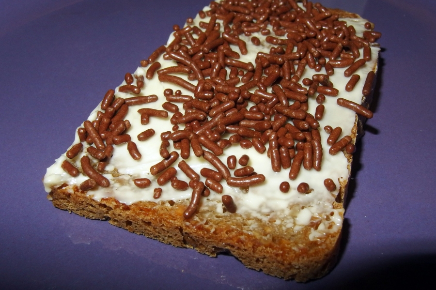 Eine Scheibe Graubrot wird mit Butter oder Margarine bestrichen und mit Schokoladenstreuseln bestreut.