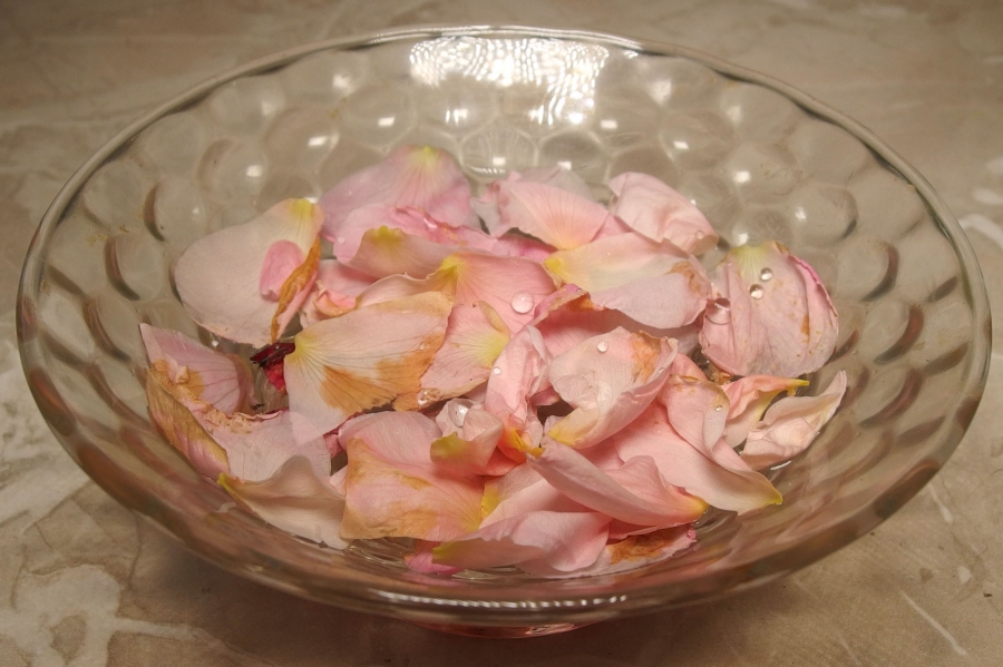Rosenblüten und Rosenöl in einer Schale - eine wohlriechende Deko