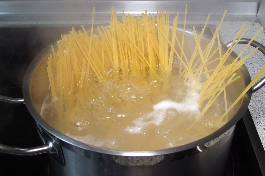 Die Spaghetti mittig in den Topf stellen und kreisförmig mit fließender Handbewegung verteilen. So sind sie schön um den ganzen Topf verteilt, bis die im Wasser stehende Seite weich wird und sie ganz versinken.