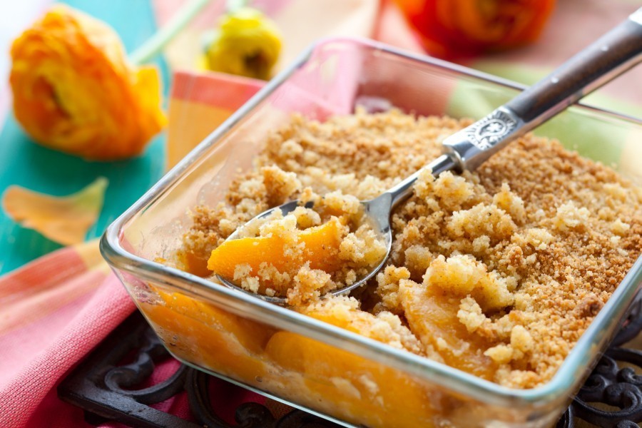 Ein Pfirsich-Crumble ist schnell hergestellt und ein fruchtig-süßes Dessert für lauwarme Sommerabende.