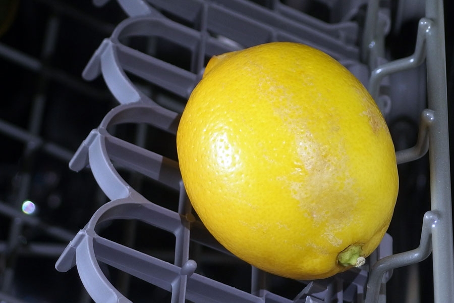 Wachs an der Zitrone mithilfe des Geschirrspülers entfernen.