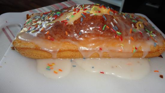 Ein Wattenapfkuchen mit Zuckerguss und bunten Streuseln liegt auf einem weißen Schneidebrett.