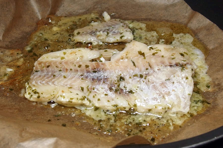 Mit dem Auslegen des Backpapiers in der Pfanne kann der Fisch nicht anbacken und der Fleischsaft aus dem Fisch bleibt erhalten, sodass der Fisch in seinem eigenen Saft gart.