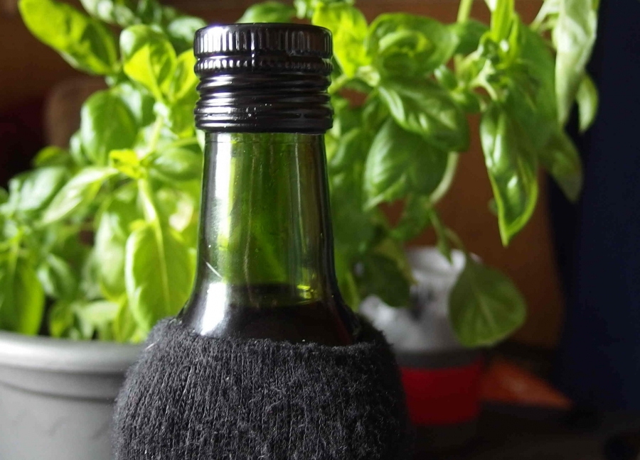Selbst gemachte Kräuteröle in hellen Flaschen mithilfe einer Socke dunkel aufbewahren: Vitamine gehen somit nicht so schnell verloren.