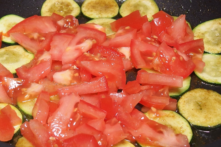 Die in Scheiben oder Stücke geschnittenen Tomaten hinzufügen, 5 Minuten leicht köcheln lassen.