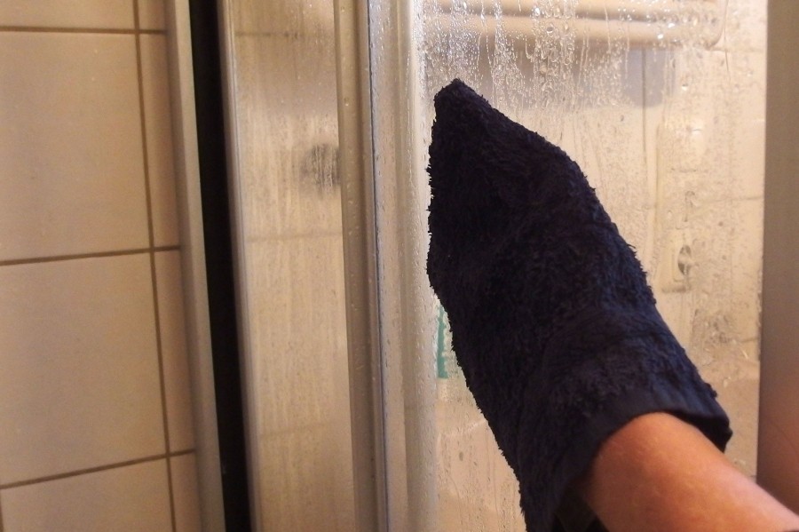 Ein alter ausrangierter schon harter Waschhandschuh wird mit Essigessenz getränkt und damit Duschwand und Fliesen entkalkt.