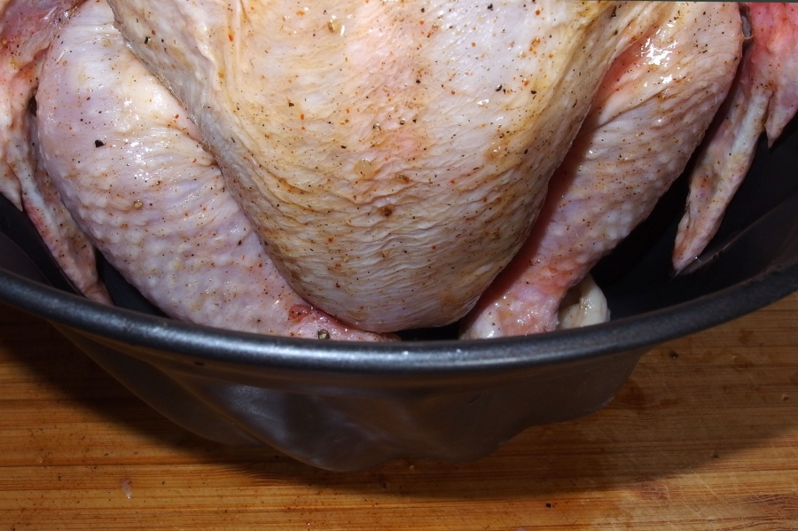 Den Backofen auf 180°C vorheizen. Das Hühnchen mit der Öffnung in eine Guglhupfform setzen.