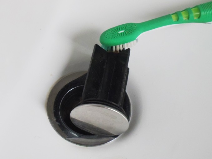 Abflussstöpsel im Waschbecken mit alter Zahnbürste reinigen