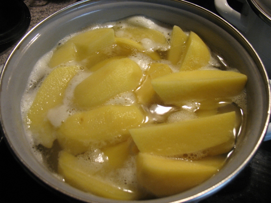 Mit kochendem Wasser aus dem Wasserkocher die Kartoffeln übergießen.