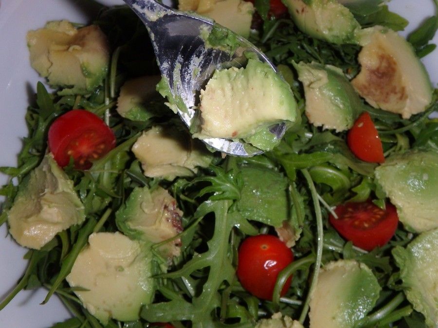 Avocadostücke auf den Rucola Salat geben.