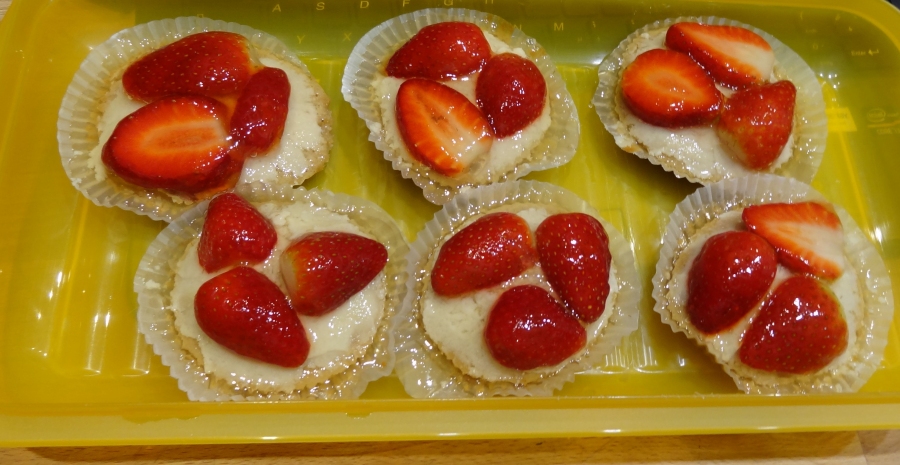 Cupcakes mit dick geschnittenen Erdbeeren großzügig belegen und mit Gelee glasieren.