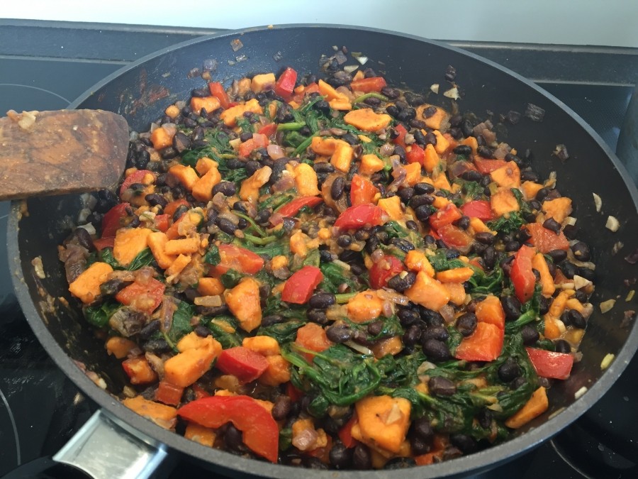 Die Paprika, die gekochten Süßkartoffeln, die schwarzen Bohnen oder die Kirchererbsen und den Spinat hinzugeben. Solange kochen, bis der Spinat zusammenschnurrt.