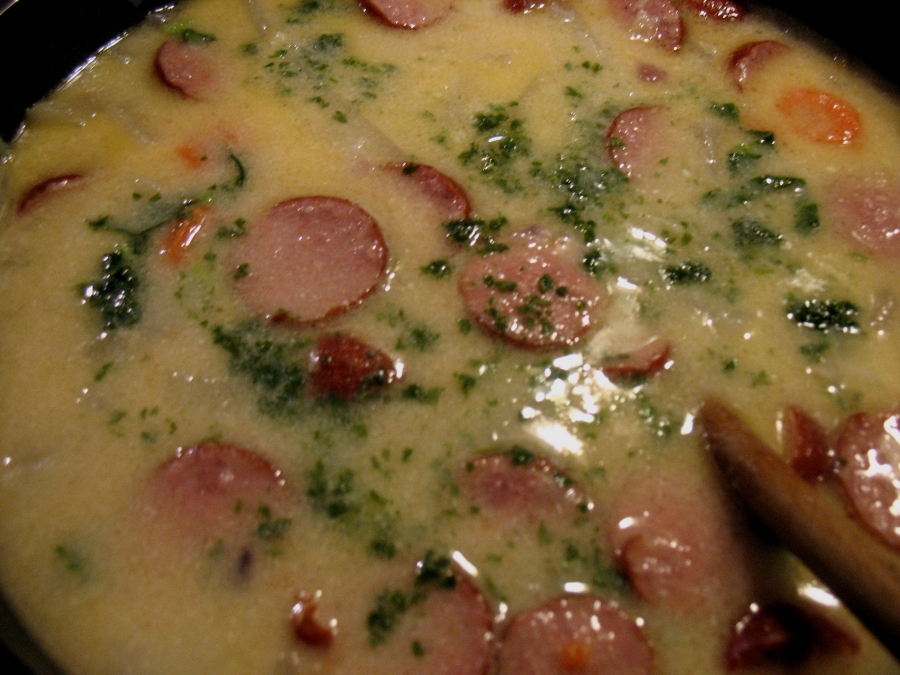 Die bunte Kohlrabi-Möhren-Suppe mit Cabanossi wird mit gehackten Kräutern serviert.