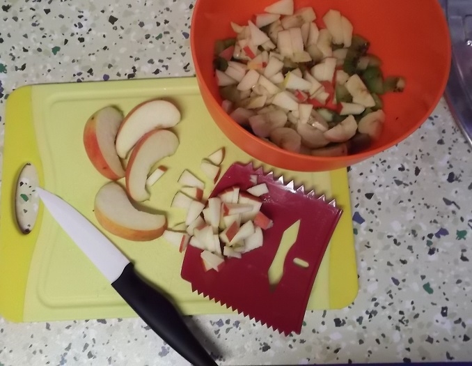 Klein geschnittenes Obst oder Gemüse mithilfe eines Teigschabers in die Schüssel geben.