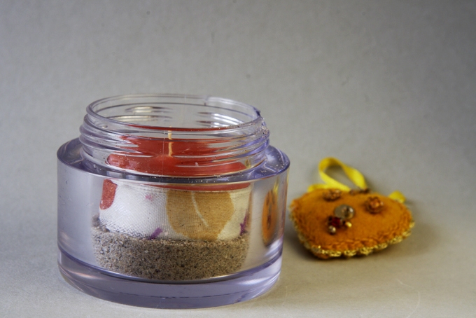 Leere Cremedose aus Glas als Kerzenhalter für ein schön dekoriertes Teelicht.