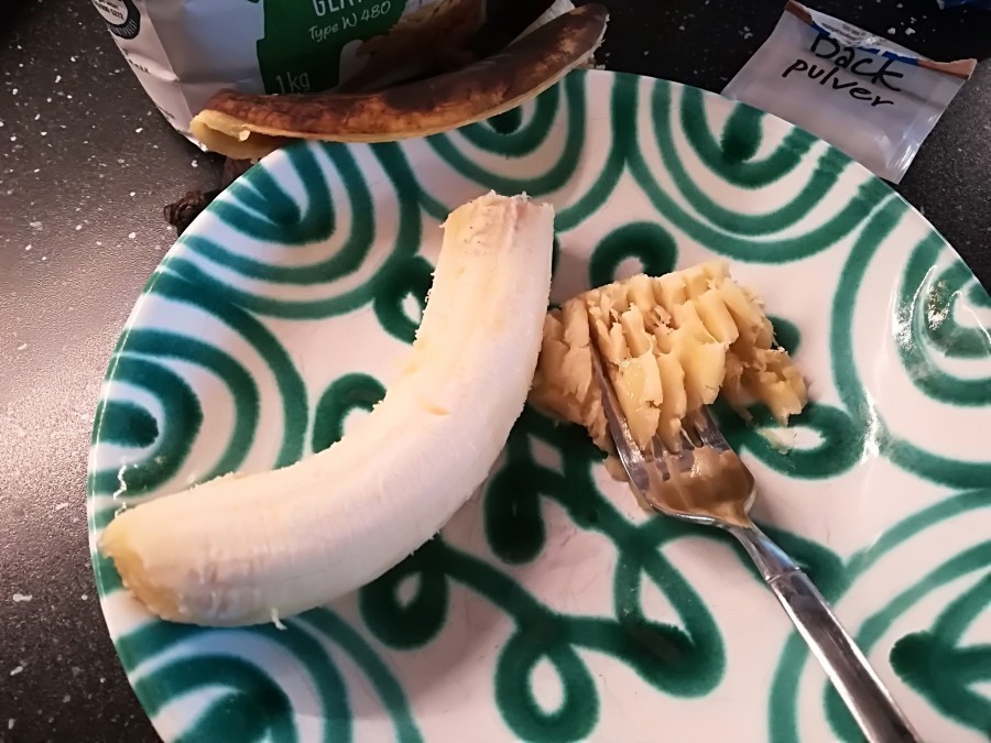 Die Banane mit der Gabel in einem Suppenteller zerdrücken, bis keine großen Stücke mehr zu sehen sind.