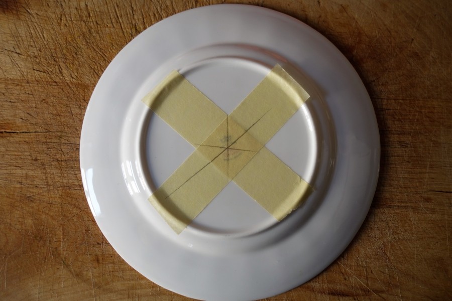 Vor dem Bohren mit Malerkrepp ein Kreuz auf die untere Seite des Tellers kleben und den Mittelpunkt zum Bohren mit Bleistift und Lineal einzeichnen.