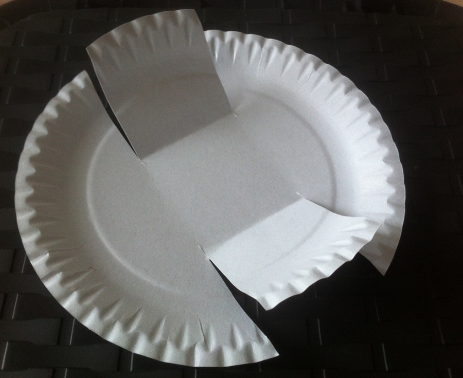 Den Pappteller auf zwei Seiten zweimal einschneiden und die eingeschnittene Fläche hochklappen.