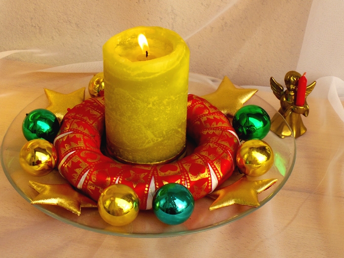 Diese weihnachtliche Tischdeko ist schnelle gemacht: Schöne Bänder, kleine Weihnachtskugeln und sonstige Teile sind oft vorhanden, eine Kerze ebenso.
