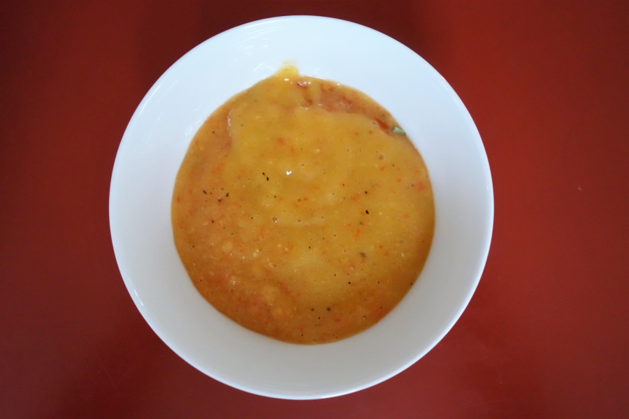 Die Erbsensuppe wird in einen tiefen Teller gefüllt und etwas von der Mango-Tomaten-Mischung auf die Suppe gegeben.