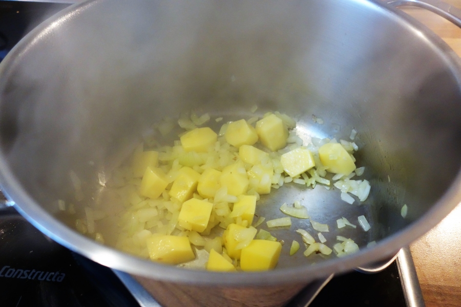 In einem Topf die Zwiebel in etwas Olivenöl andünsten. Die Kartoffeln zugeben und kurz mit dünsten. Mit Gemüsefond ablöschen und zugedeckt bei mittlerer Hitze 15 Minuten kochen lassen.