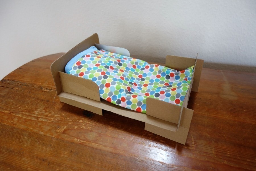 Aus einem Kopierpapier-Karton lässt sich ein niedliches Puppenbett basteln.