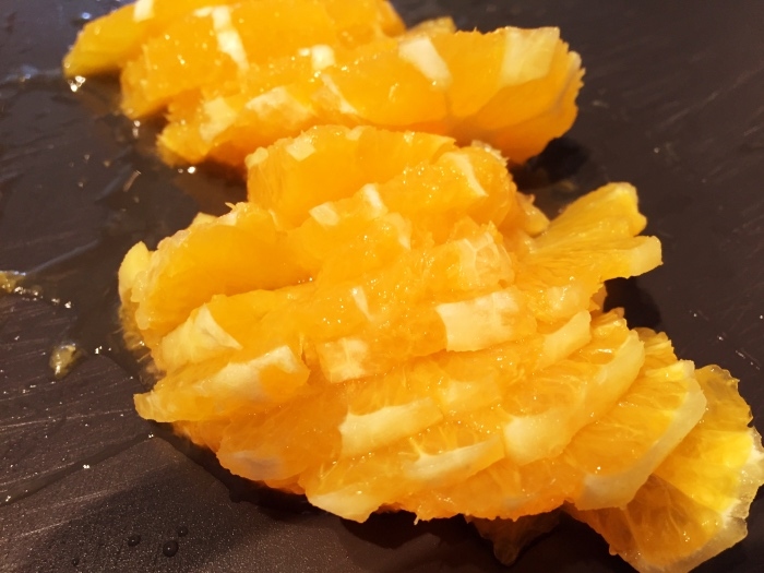 Orange schälen, halbieren und in feine Scheiben schneiden. (Saft der  dabei entsteht nicht wegschütten).