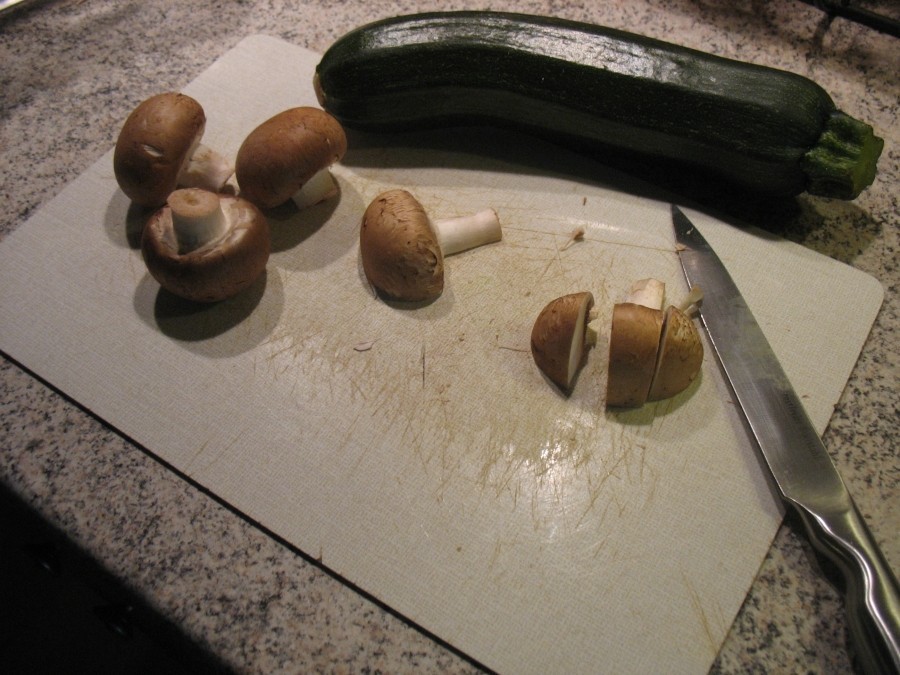Die Zucchini waschen und in kleine Stücke schneiden, Champignons putzen und klein schneiden.