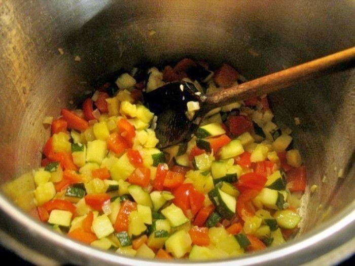 Das Gemüse zu den Zwiebeln in den Topf geben und kurz mit anbraten, das Mehl hinzufügen, unterrühren und alles gut anrösten.