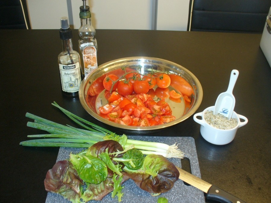 Die Zutaten vorbereiten: Tomaten teilen. Salat putzen, waschen und trocken schleudern.