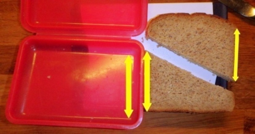 Man schneidet das Brot diagonal durch, allerdings nicht von Ecke zu Ecke, sondern ein Stückchen weit von den Ecken entfernt. Man nimmt einfach als Maß die kürzere Seite der Brotbox. 