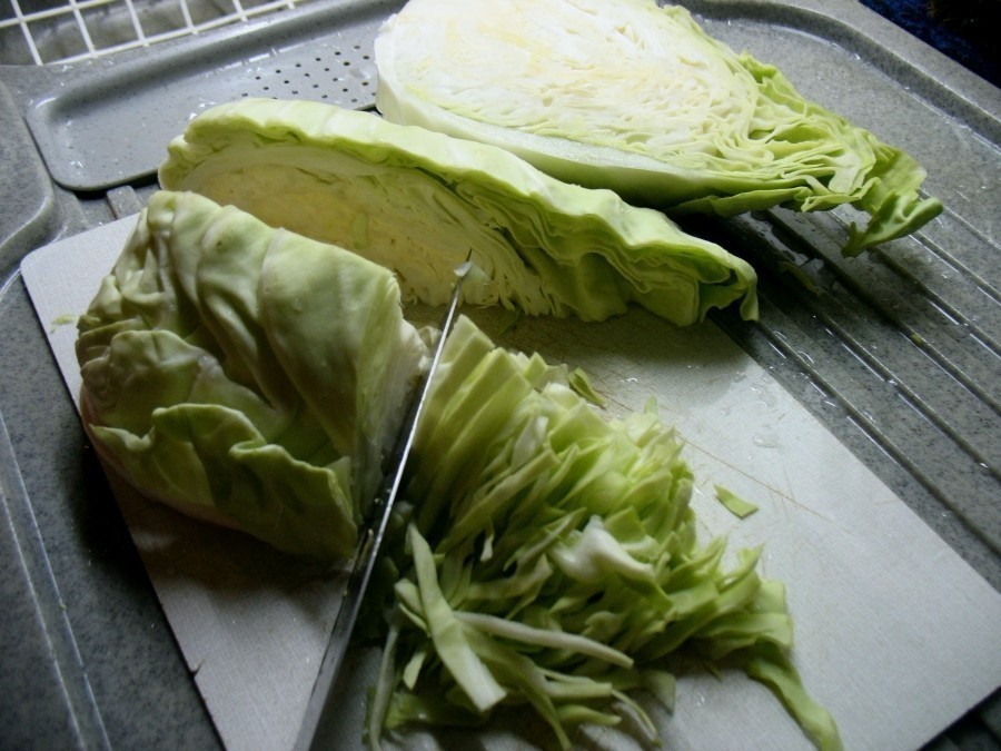 Für den vegetarischen Spitzkohlsalat muss der Kohl in sehr feine Streifen geschnitten werden, wie hier zu sehen.