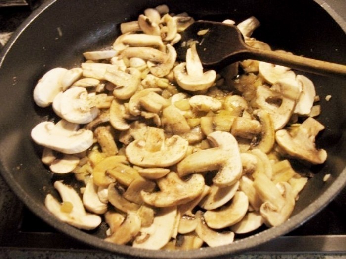 Die Champignonscheiben, Zwiebel- und Knoblauchwürfel werden in einer Pfanne mit etwas Butterschmalz kurz angedünstet.