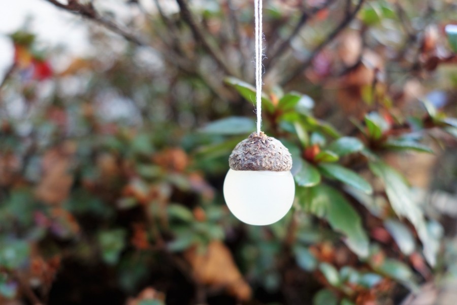 Dazu benötigt man kleine Perlen, Murmeln oder kleine Filzkugeln. Damit die Hütchen an den Weihnachtsbaum gehängt werden können, wird zuerst mit einer spitzen Nadel Nähseide durch den oberen Teil der Kappe gezogen und verknotet...