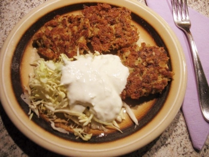 Knusprig gebratene Haferflocken-Puffer mit Schmand und Spitzkohlsalat angerichtet. Die Puffer schmecken auch kalt als kleiner Snack zwischendurch.