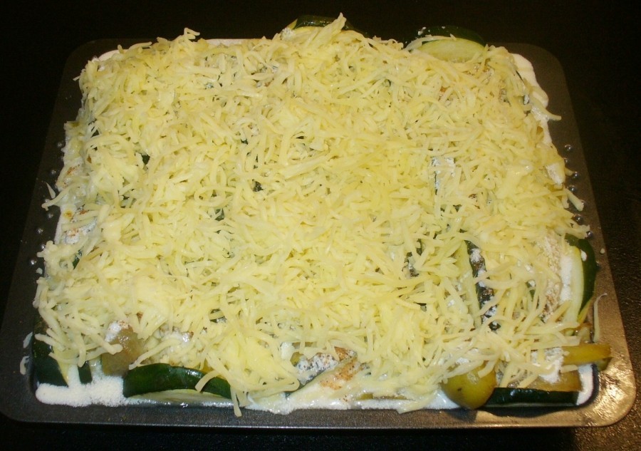 Den geschichteten Auflauf dick mit geriebenem Käse und einigen Semmelbröseln bestreuen.