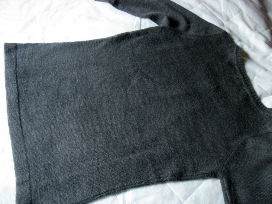 Praktische Hilfe beim Zusammenlegen von Kleidungsstücken: Pullover mit der Vorderseite nach unten auf einer glatten Unterlage.