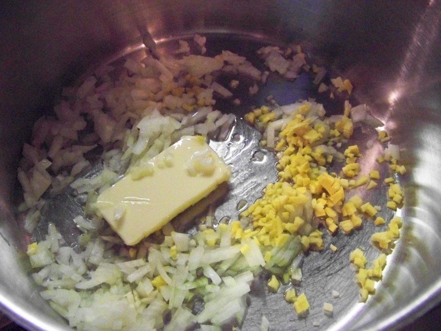 In einen entsprechend großen Topf die Butter mit dem Distelöl erhitzen und die Zwiebel, den Ingwer und die Knoblauchzehe anschwitzen.